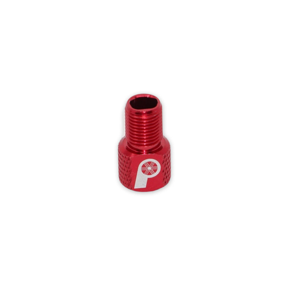 The Prestacycle Prestadapter TUBELESS is a small, red, lightweight alloy Schrader-to-Presta valve adapter and core remover with threading and a white P-and-wheel logo, shown isolated on a white background.