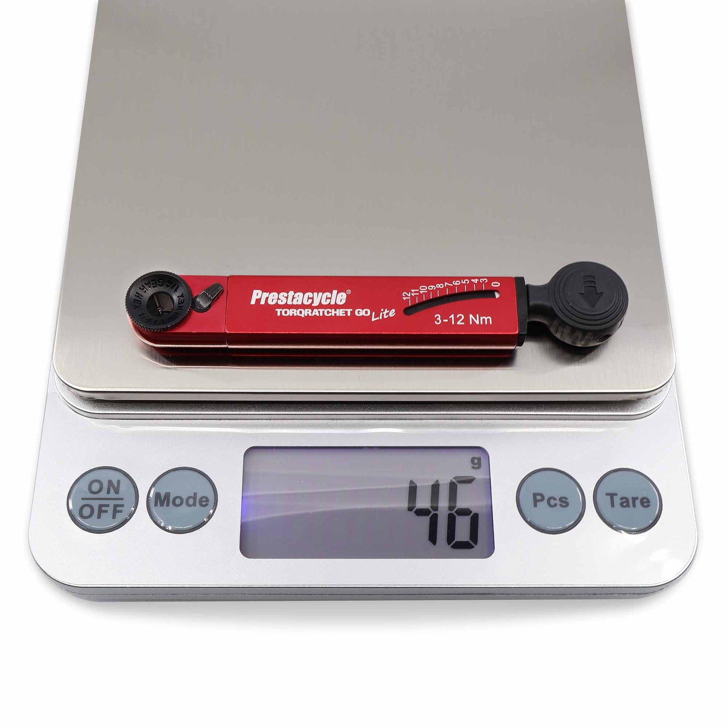 A red Prestacycle TorqRatchet GO Lite portable 3~12Nm torque multi-tool ratchet, by Prestacycle, sits on a digital kitchen scale reading 46 grams; the scale features On/Off, Mode, Pieces, and Tare buttons.