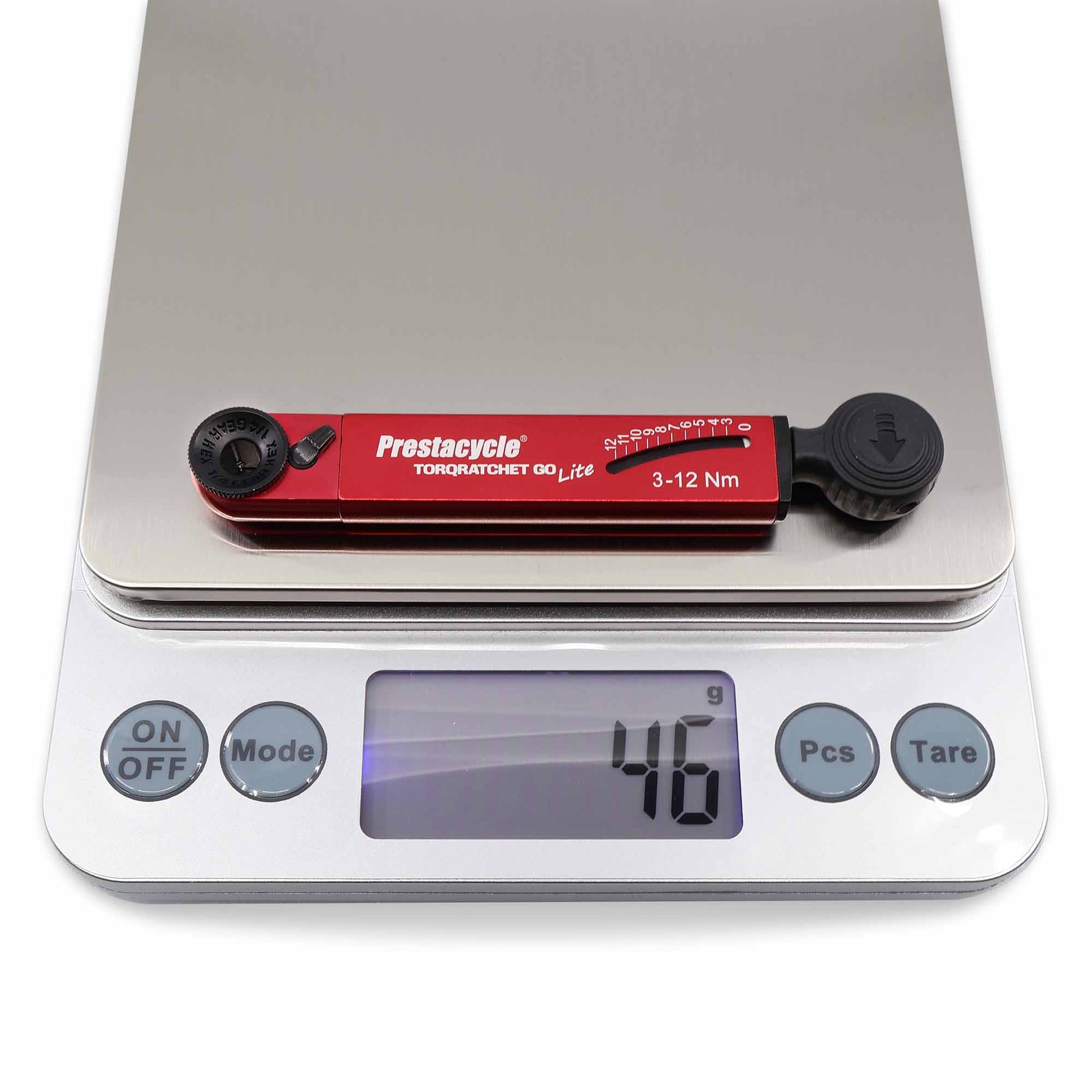 A red Prestacycle TorqRatchet GO Lite portable 3~12Nm torque multi-tool ratchet, by Prestacycle, sits on a digital kitchen scale reading 46 grams; the scale features On/Off, Mode, Pieces, and Tare buttons.