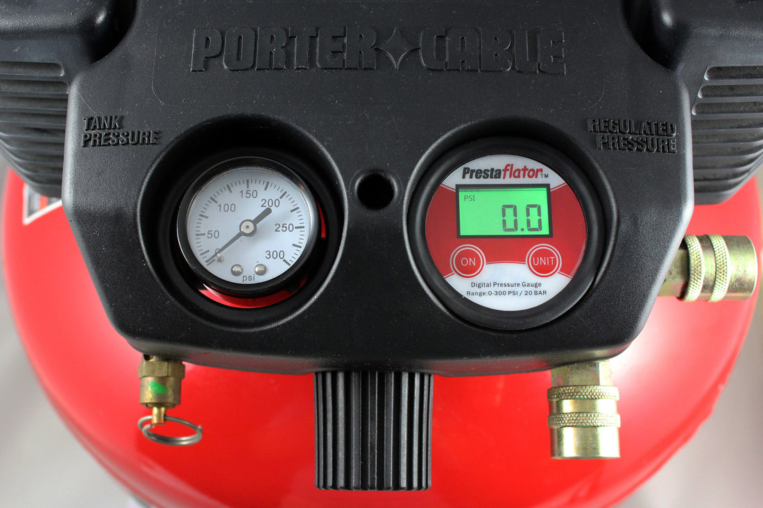 Close-up of a Prestacycle Prestaflator Digital Gauge for Air Compressors &amp; Floor Pumps with an analog tank pressure gauge, both showing clear dials and connectors, set against a vivid red background.