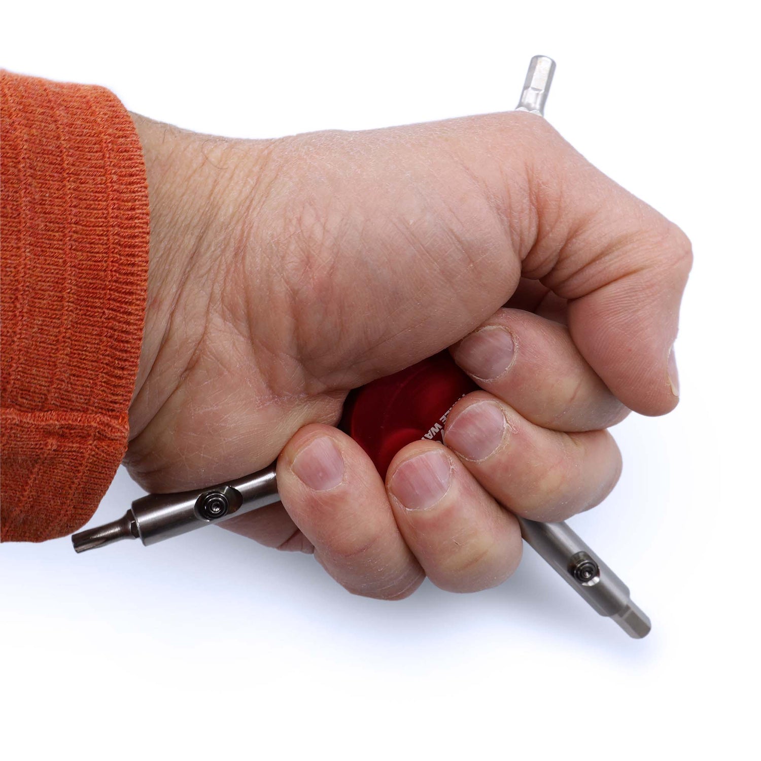 A hand grips the Prestacycle Professional Three Way Y Bits Tool Kit with its red handle, ready to quickly swap 1/4″ Hex bits. The user, in an orange long-sleeve shirt, shows two tool ends protruding from their fist.