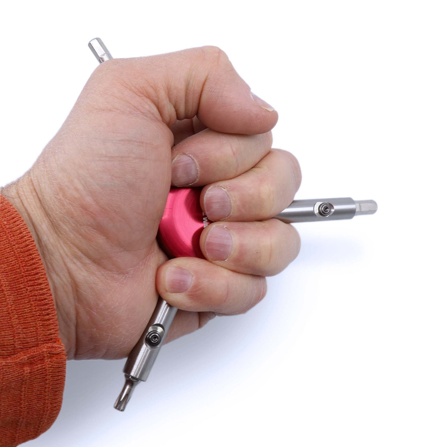 A hand in an orange sleeve grips the Prestacycle Professional Three Way Y Bits Tool Kit, a pink circular tool by Prestacycle with two metal rods extending outward, compatible with 1/4″ Hex bits, shown against a white background.