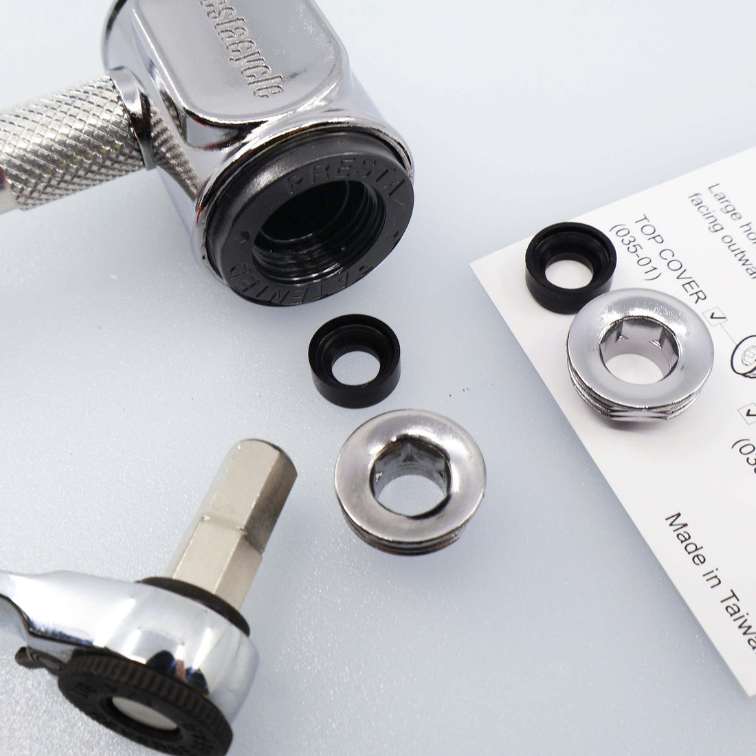 A close-up of a Prestacycle Prestaflator Pro Presta Head Rebuild Kit shows the ratchet tool, metal washers, black rubber rings, and paper manual on a light surface, highlighting the components for assembly or repair.