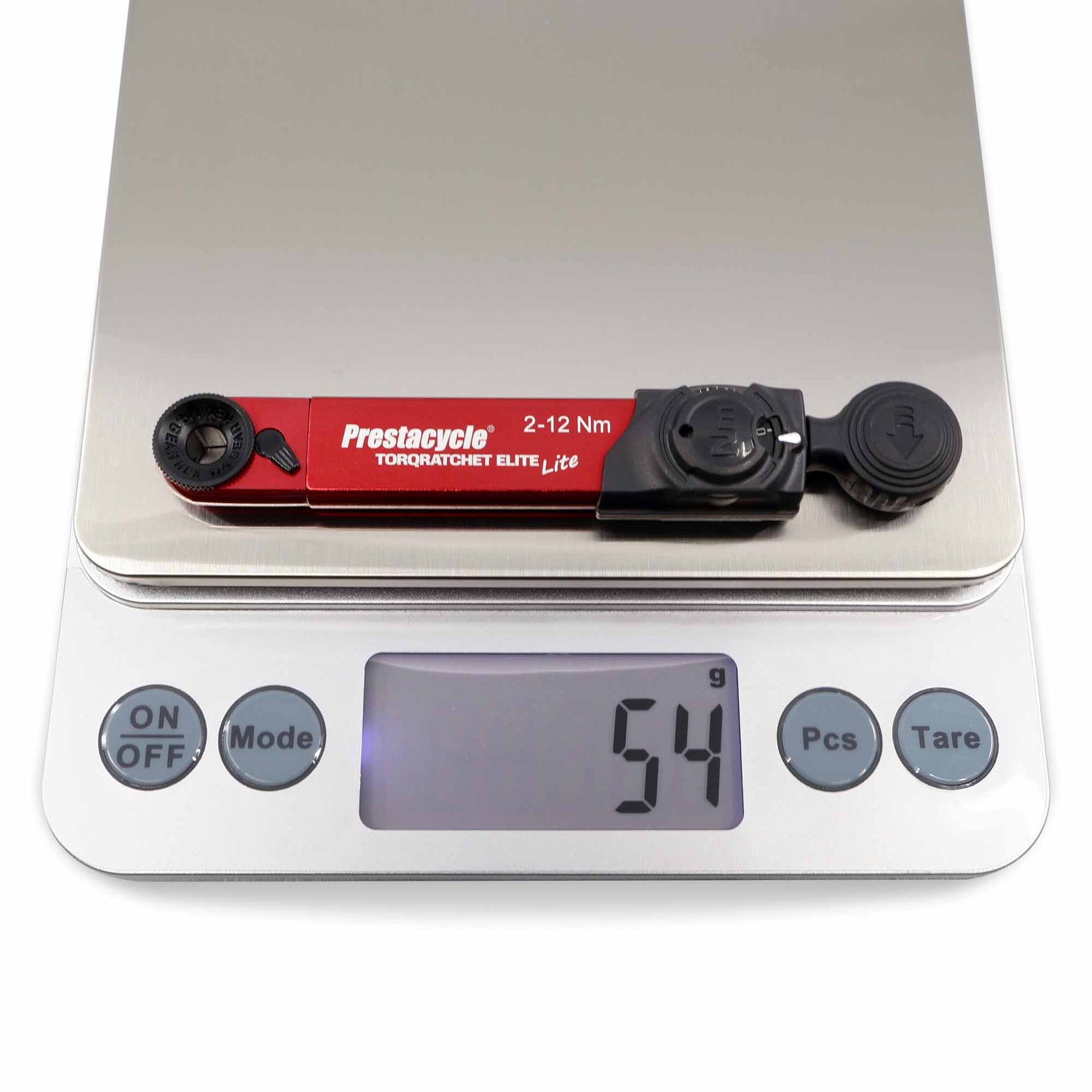 A Prestacycle TorqRatchet ELITE Lite portable torque multi-tool ratchet in red is shown on a digital scale reading 54 grams. The scale features gray ON/OFF, Unit, Pcs, and Tare buttons.