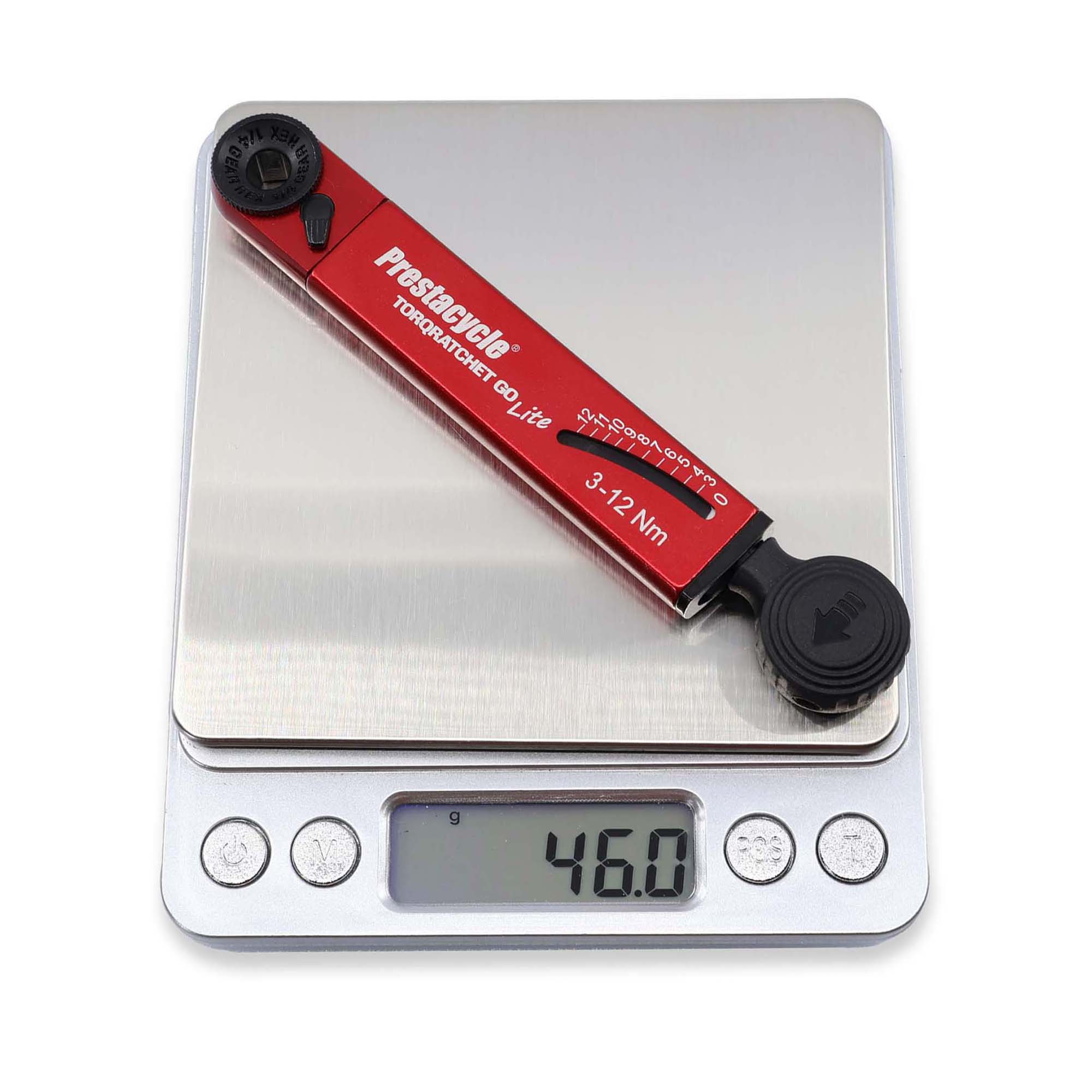 A red Prestacycle TorqRatchet GO Lite (3–12Nm), a portable multi-tool ratchet, rests on a digital kitchen scale showing 46.0 grams. The reversible ratchet feature allows for easy torque adjustments.